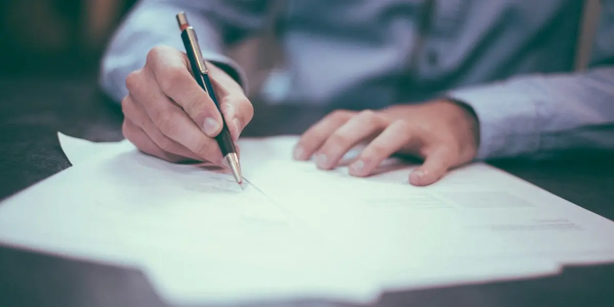 Hand signing a contract with a pen