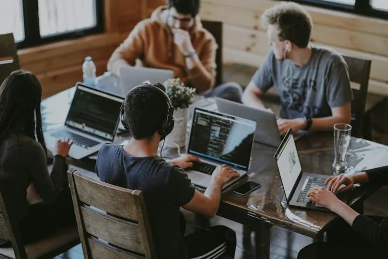 Equipo de personas trabajando con sus portátiles alrededor de una mesa